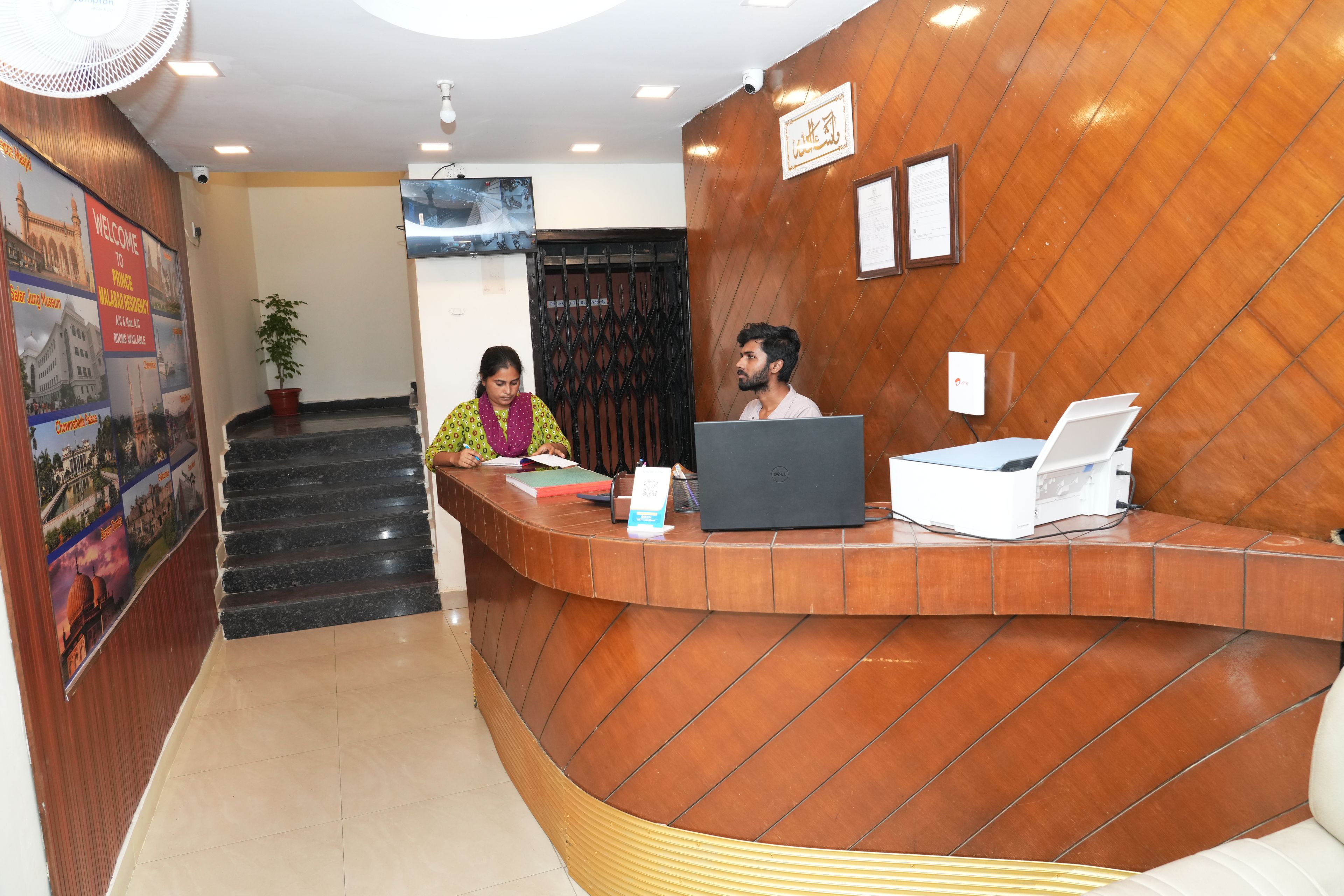 A reception desk with a curved design, a potted plant, and a poster on the wall.