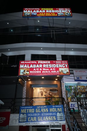 Ein Gebäude mit einem Schild für MALABAR RESIDENCY, das klimatisierte (A/C) und nicht klimatisierte Zimmer anwirbt.
