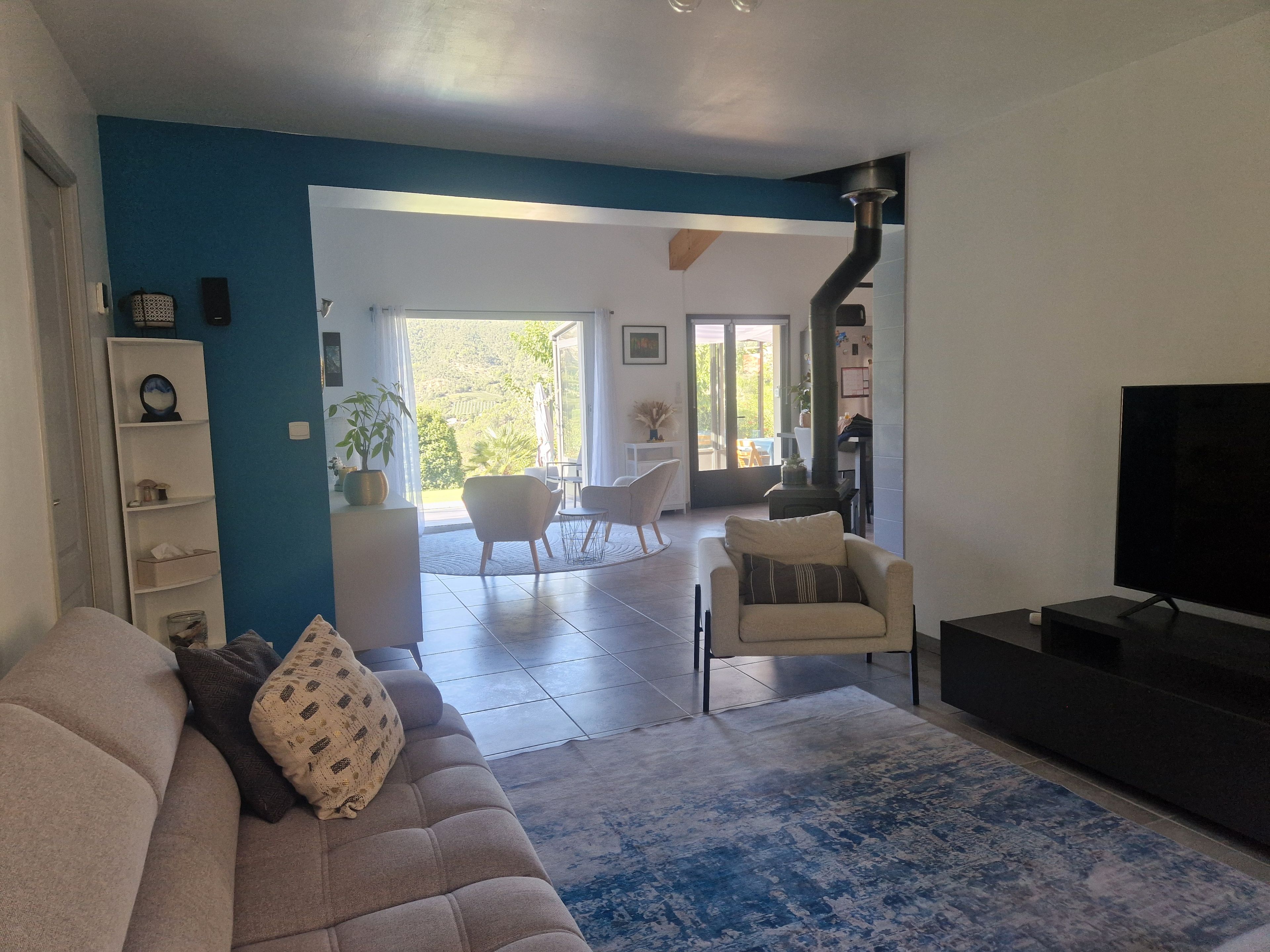 Una sala de estar moderna con un sofá, un televisor y un amplio ventanal.