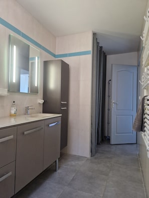Ein Badezimmer mit Spiegel, Waschbecken, Schrank und Handtuchhalter.