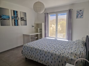 Ein Schlafzimmer mit einem Bett, einem Schreibtisch und einem Fenster mit Vorhängen.