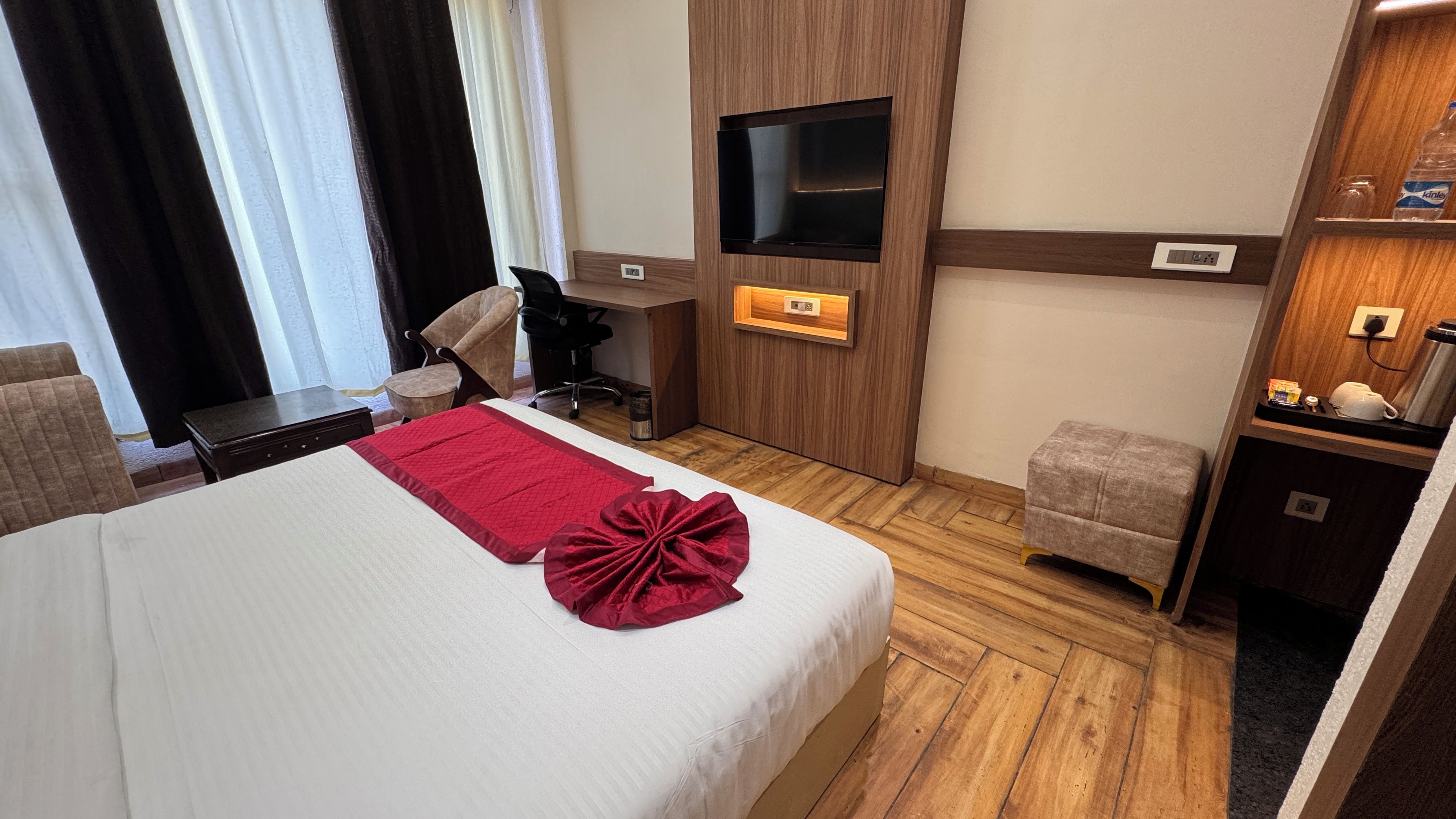 Habitación de hotel con cama, escritorio, silla, televisión y una pequeña kitchenette.