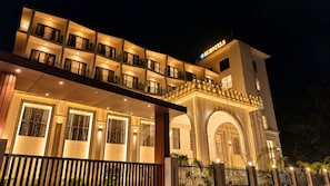 Un hotel de varios pisos con balcones, una entrada bien iluminada y un cartel que indica que es un hotel.