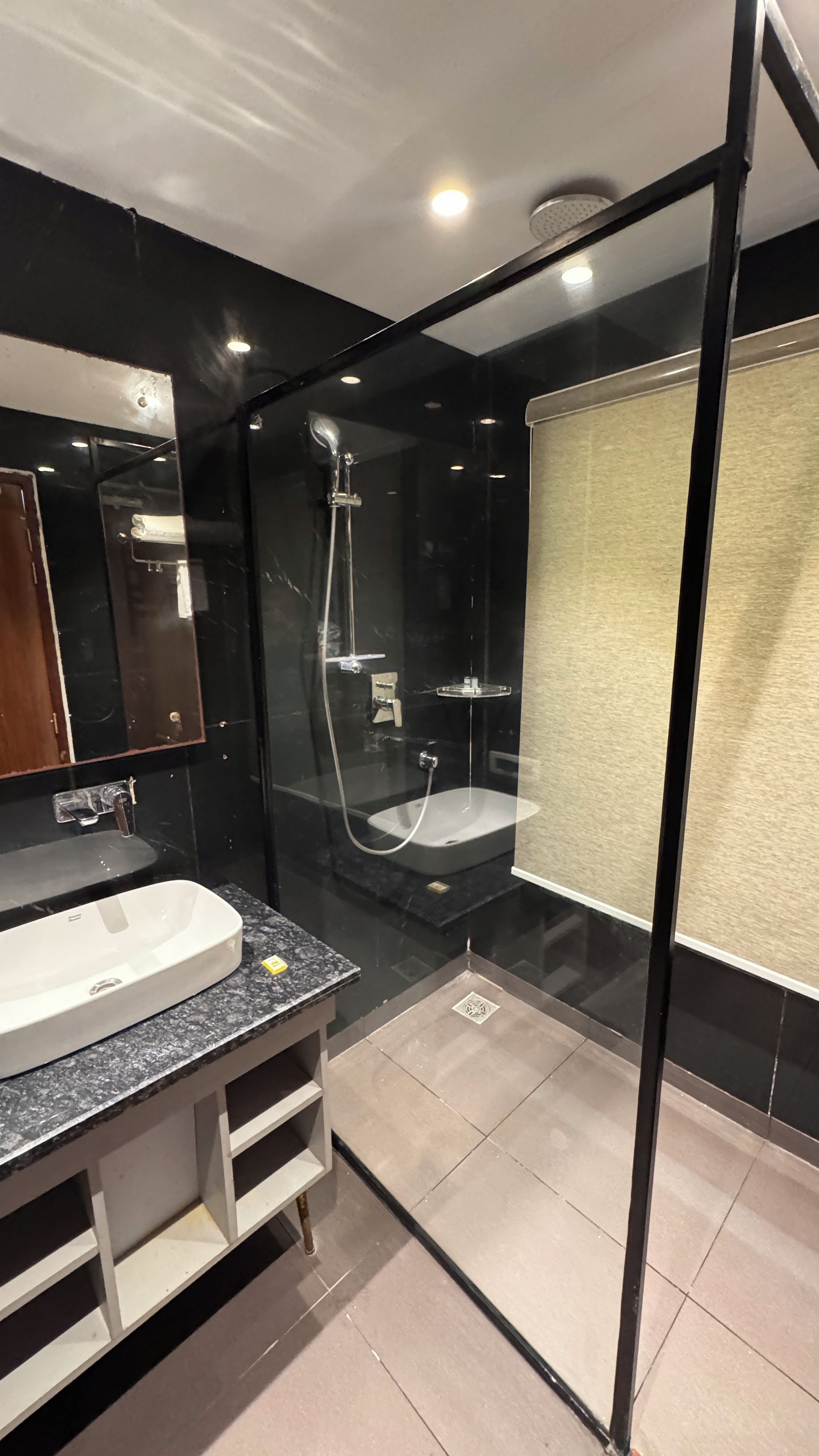 Un baño moderno con ducha envuelta en vidrio, un lavamanos blanco y un espejo.