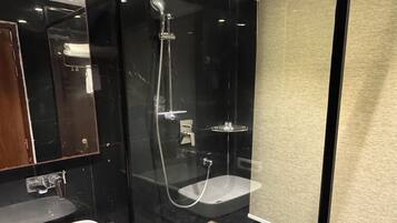 Un baño moderno con ducha envuelta en vidrio, un lavamanos blanco y un espejo.