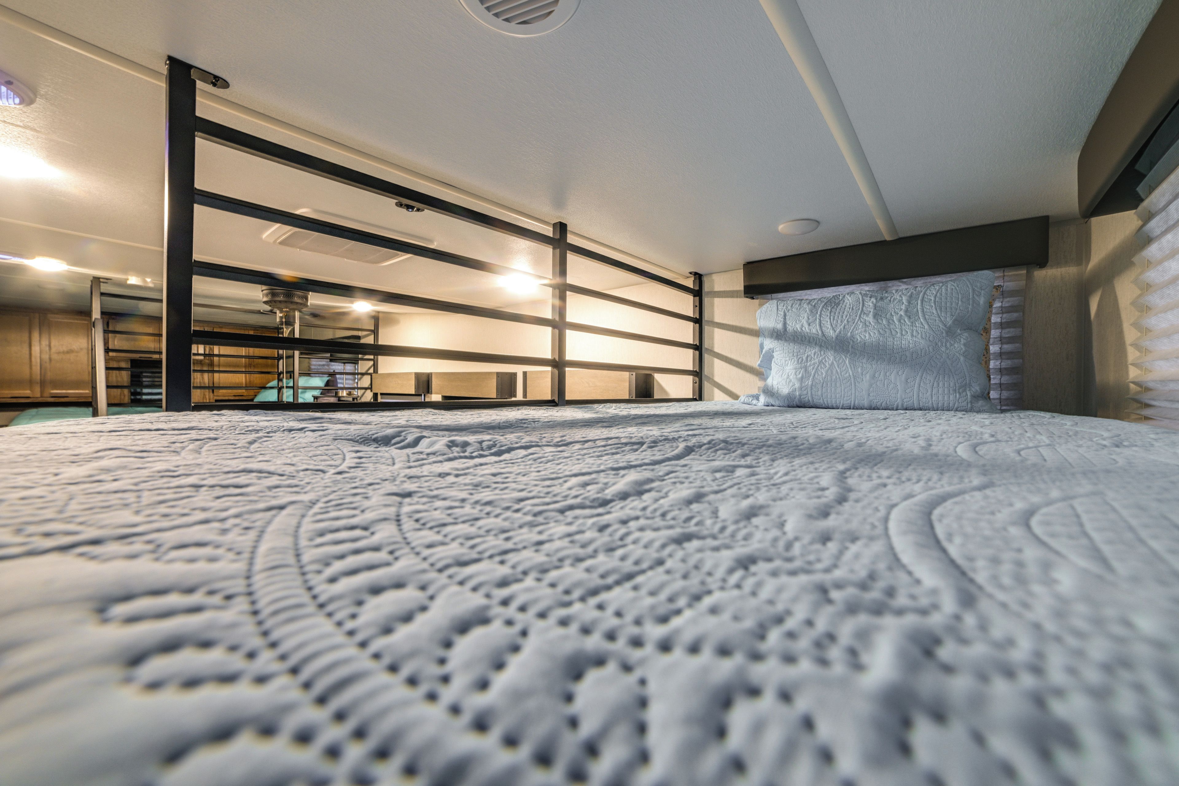 A bedroom with a large bed, a headboard, and a ceiling fan.