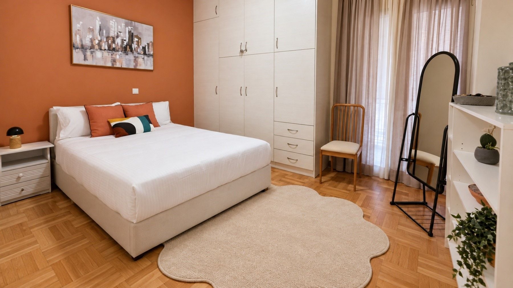 A bedroom with a bed, a nightstand, a wardrobe, a chair, a mirror, and a potted plant.
