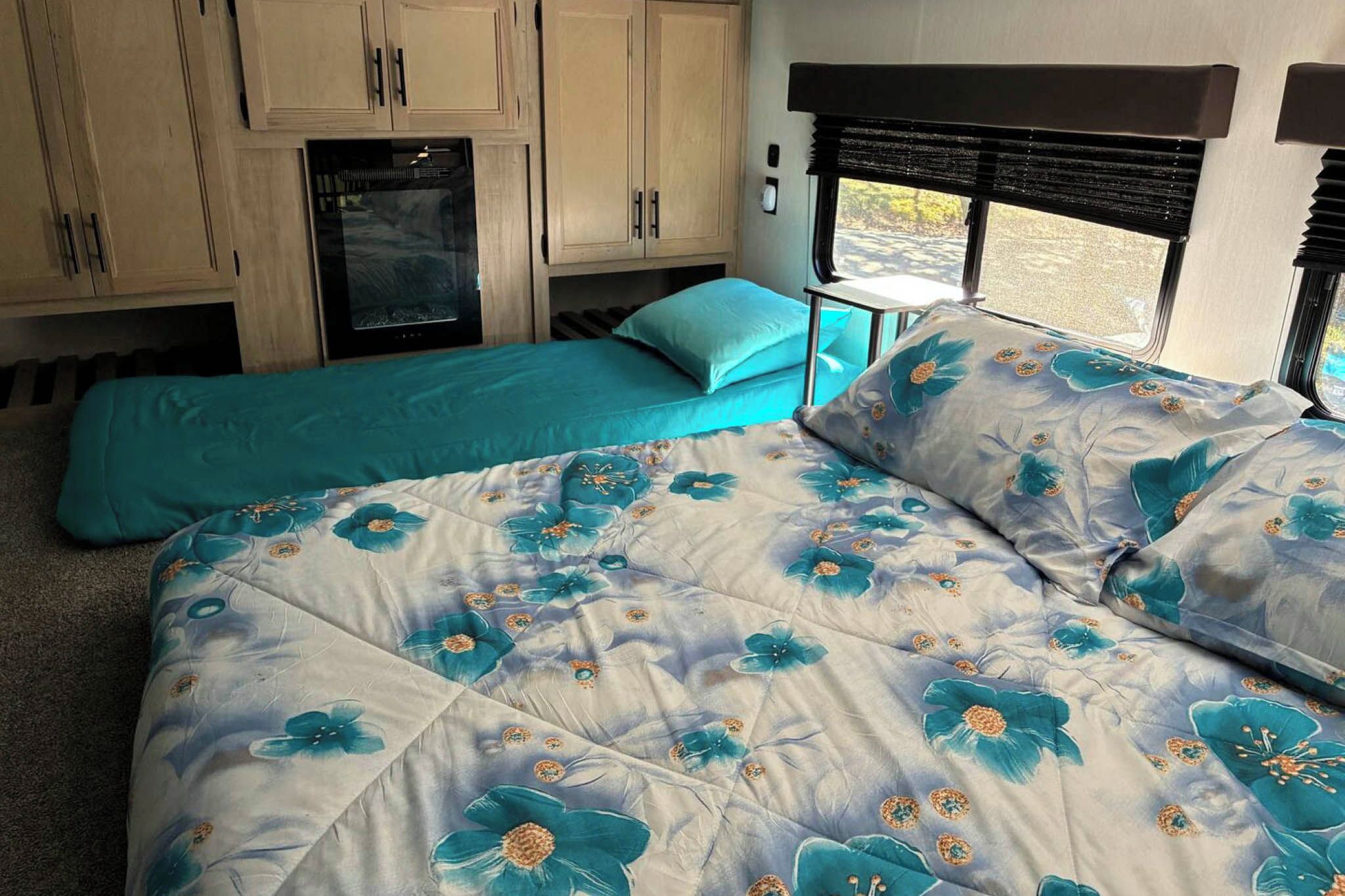 A bedroom with a bed, a small table, and a window with blinds.
