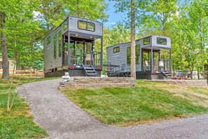 Two modern, elevated wooden structures with external staircases, a gravel path, and surrounding greenery. - Fireside Nights! Tiny Home 1 Mi to Kentucky Lake (Springville)