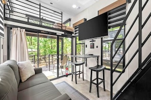 A modern interior with a sofa, a small bar area, and a TV mounted on the wall. - 1 Mi to Kentucky Lake! 'Special Place' Tiny Home (Springville)