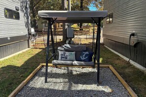 A swing set with a metal frame and a padded seat, surrounded by gravel and grass. - 1 Mi to Kentucky Lake! 'Special Place' Tiny Home (Springville)