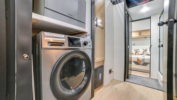 A compact, modern laundry room with a front-loading washing machine, a dryer, and a small control panel with instructions.