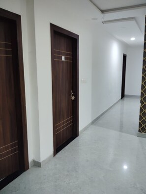 A corridor with two wooden doors, a patterned wall, and a tiled floor. - Akash Inn A Boutique Hotel (Agra)