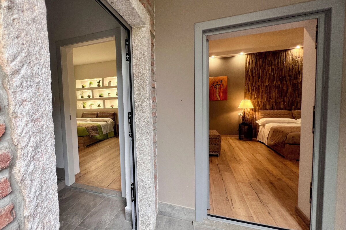 Habitació d'hotel amb llit, taulell de nit, làmpada i paret amb un relleu decoratiu.
