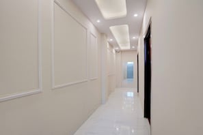 A corridor with white walls, recessed ceiling lights, and a marble floor. - Hotel O Blue Hills (Jaipur)