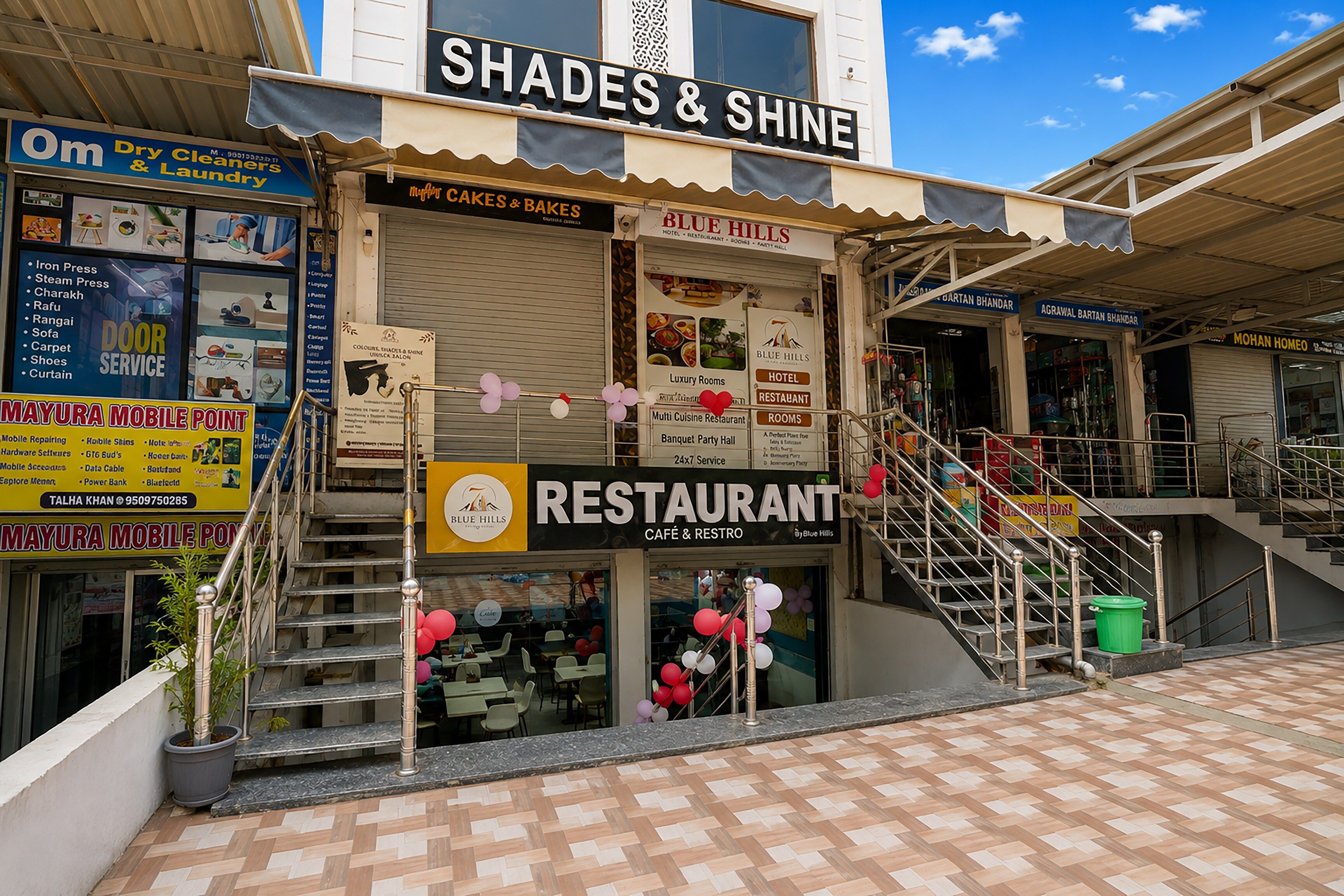 A multi-story building with a restaurant on the ground floor, a dry cleaners on the second floor, and a sign for 'Shades & Shine' on the top.