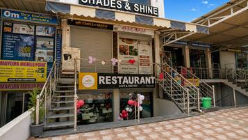 A multi-story building with a restaurant on the ground floor, a dry cleaners on the second floor, and a sign for 'Shades & Shine' on the top.