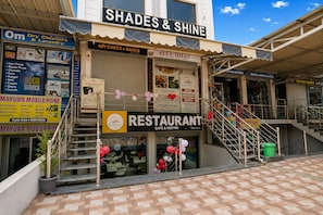 A multi-story building with a restaurant on the ground floor, a dry cleaners on the second floor, and a sign for 'Shades & Shine' on the top. - Hotel O Blue Hills (Jaipur)