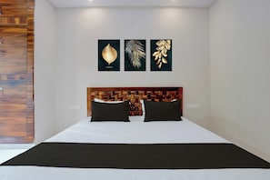 Ein Schlafzimmer mit einem hölzernen Kopfteil, einem Bett mit weißer Bettwäsche und drei gerahmten Kunstwerken an der Wand.