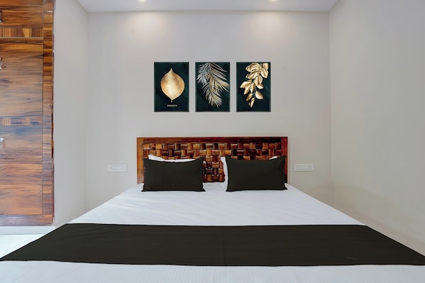 A bedroom with a wooden headboard, a bed with white bedding, and three framed artworks on the wall. - Hotel O Blue Hills (Jaipur)