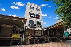 A hotel with a sign for 'OYO & Blue Hills Hotel' and a 'Shades & Shine Unisex Salon' below. - Hotel O Blue Hills (Jaipur)