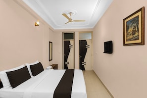 A hotel room with a bed, a ceiling fan, a painting, and a door with a unique design. - Hotel O Sunrise (Jaipur)