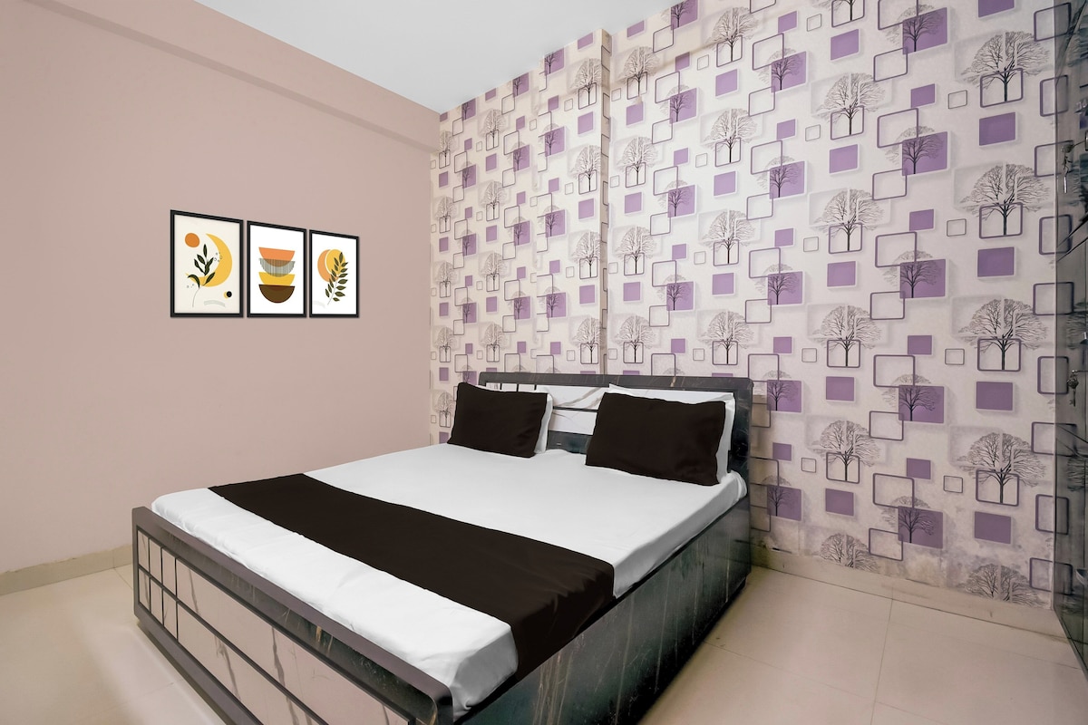 Ein Schlafzimmer mit einem Bett, einer Wand mit geometrischem Muster und drei gerahmten Kunstwerken.