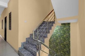 Un escalier avec des rampes en métal et un mur orné d’un motif texturé vert.