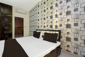 Ein Hotelzimmer mit Bett, Kleiderschrank und einer Wand mit geometrischem Muster.