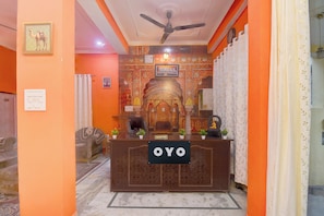 Una recepción con un letrero que dice 'OYO' en una habitación con paredes naranja y papel tapiz estampado.