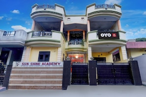 Een meerhoog gebouw met een bord waarop 'OYO Hotel Krishna Palace' en 'SUN SHINE ACADEMY' staan.