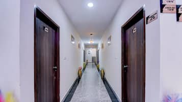 A hotel hallway with doors numbered 001 to 004, check-in and check-out signs, and framed pictures on the walls.