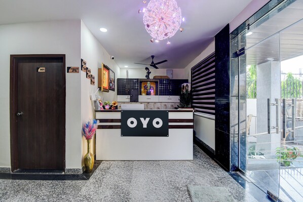 Un mostrador de recepción con un cartel que dice 'OYO' y un ventilador de techo arriba.