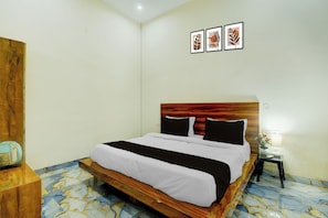 A hotel room with a bed, a nightstand, a lamp, and a wall with three framed pictures. - Hotel O The Suresh Mahal Resort (Jaipur)