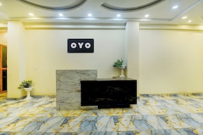 A reception desk with a marble top and a black base, a sign with the word 'OYO' above it, and a potted plant to the left. - Hotel O The Suresh Mahal Resort (Jaipur)
