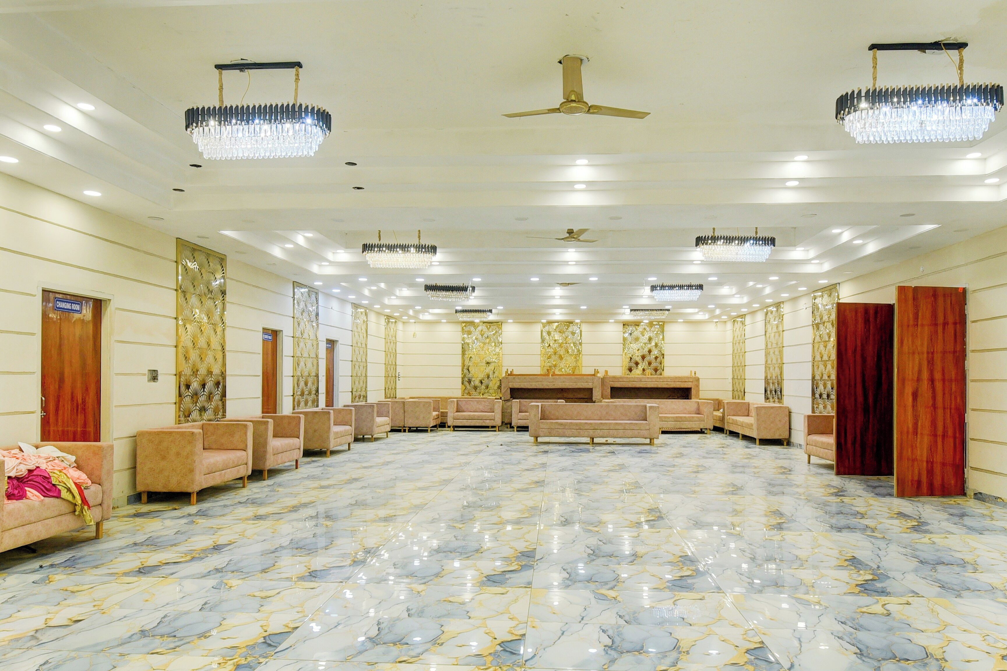 Un amplio vestíbulo de hotel con piso de mármol, varias zonas de estar y paneles decorativos en las paredes.