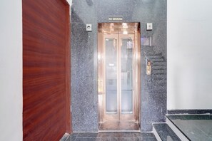 An elevator with a 'NO SMOKING' sign above it, a fire alarm, and a 'FIREMAN'S PASS' sign on the wall. - Hotel O Sanraj Hotel (Jaipur)