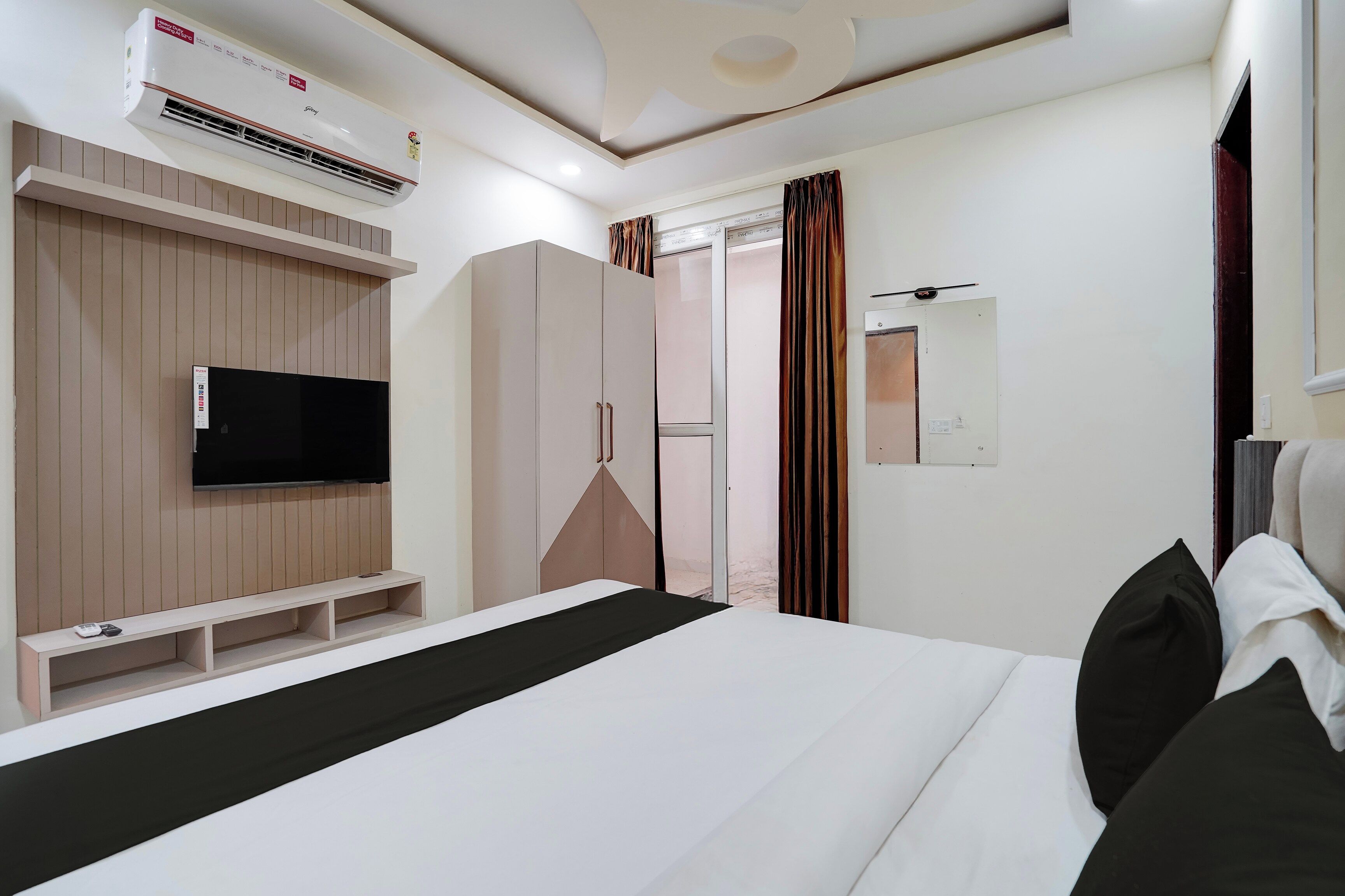 Un dormitorio moderno con cama, televisión, armario y aire acondicionado.