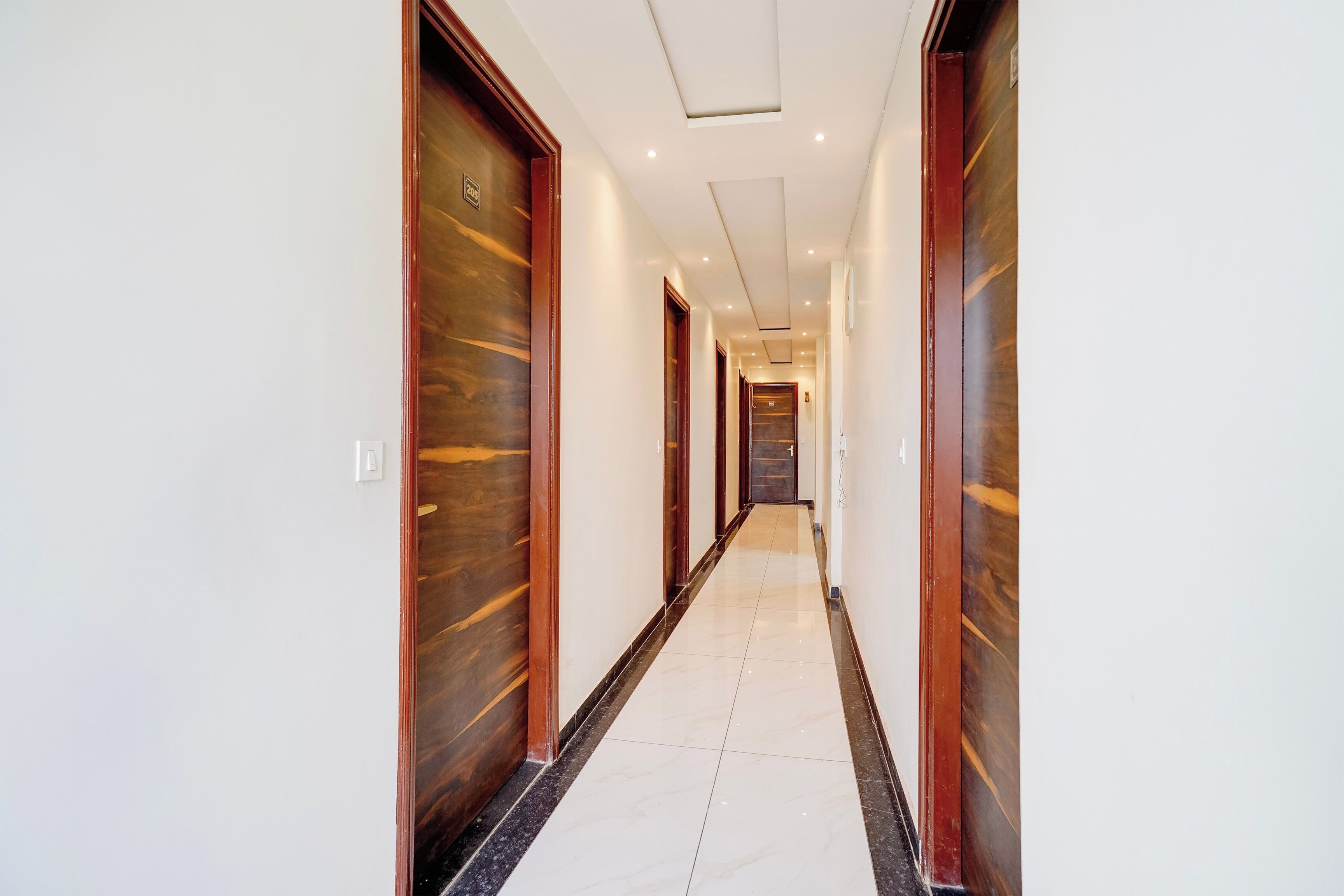 Un pasillo de hotel con puertas de madera y suelo de baldosas.