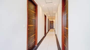 A hotel corridor with wooden doors and a tiled floor.