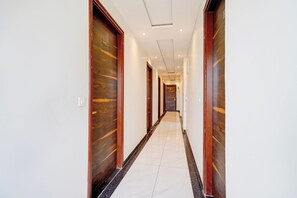 A hotel corridor with wooden doors and a tiled floor. - Hotel O Sanraj Hotel (Jaipur)