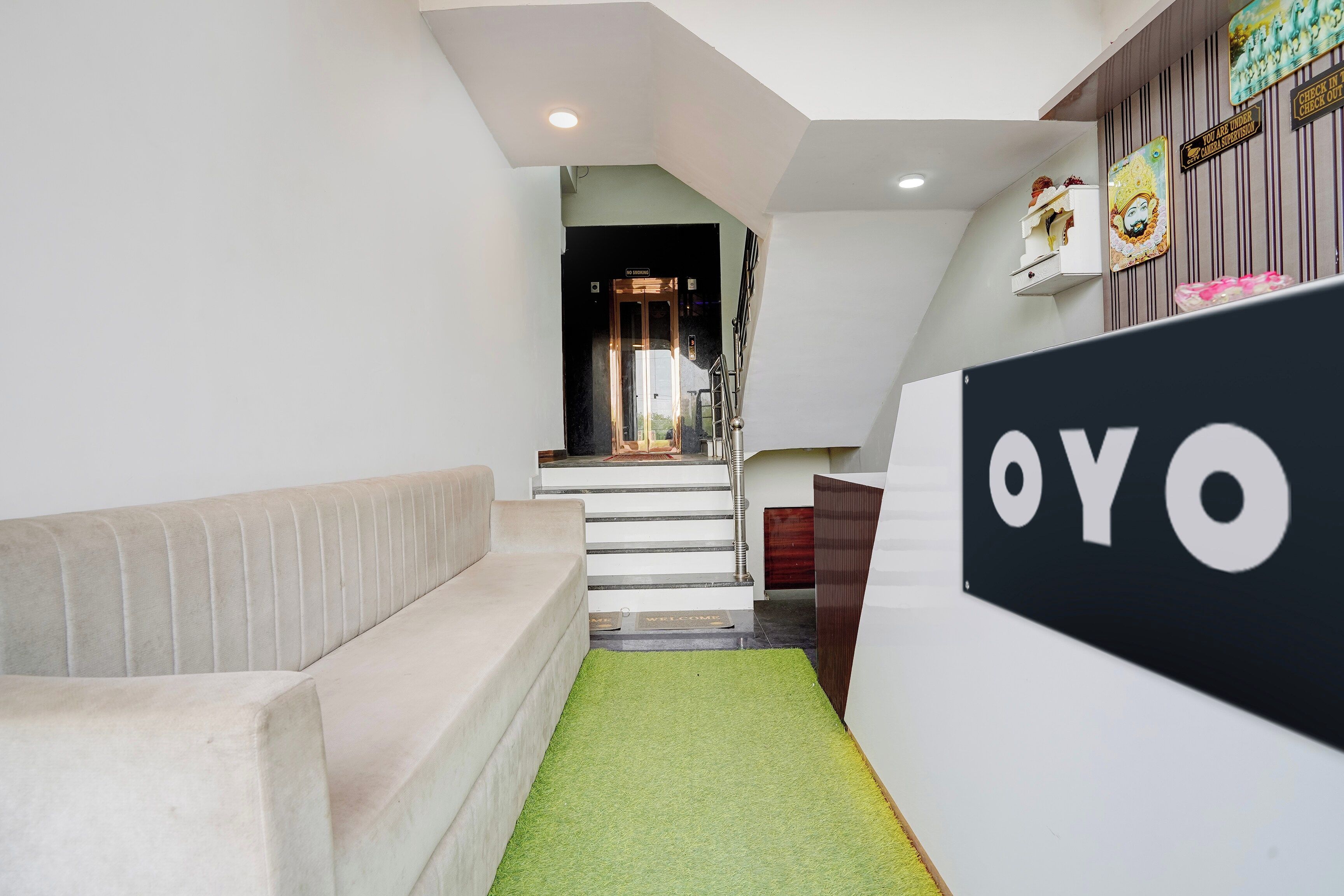 Een receptiegedeelte met een bank, een trap en een bordje met de tekst 'OYO'.