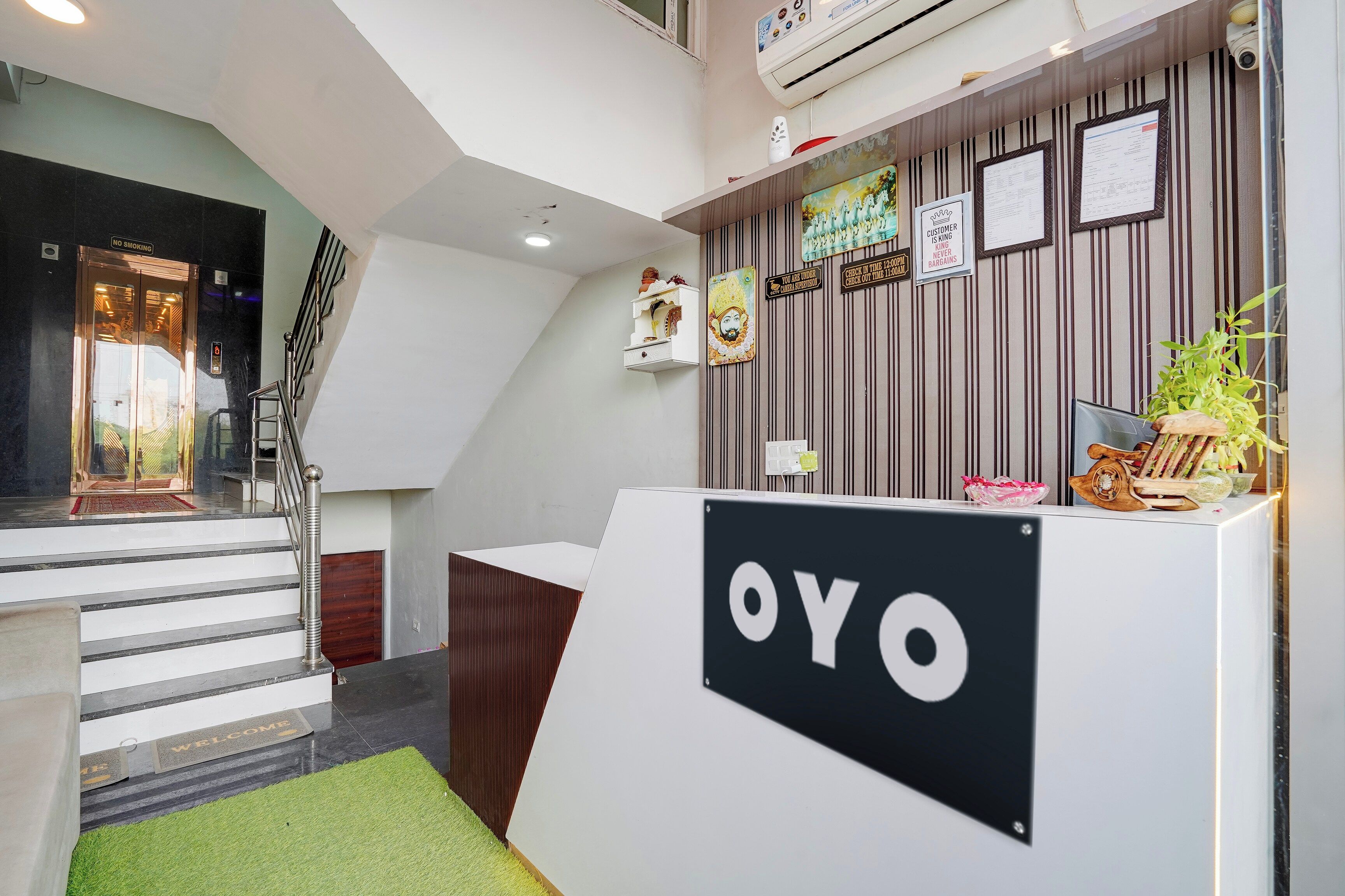 A reception area with a 'YO' sign, a staircase, and a wall with various signs and decorations.