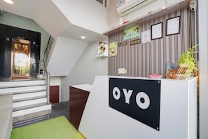 A reception area with a 'YO' sign, a staircase, and a wall with various signs and decorations. - Hotel O Sanraj Hotel (Jaipur)
