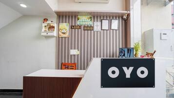 A reception desk with a sign that reads 'OYO' and a wall with vertical lines and various signs, including one that says 'CUSTOMER IS KING NEVER BARGAINS.'