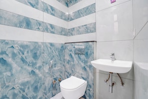 Ein Badezimmer mit einer weißen Toilette, einem weißen Waschbecken und einer Dusche mit Duschbrause.