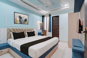 Ein Schlafzimmer mit einem Bett, einem Schreibtisch, einem Sessel, einem Fernseher und einem Deckenventilator.
