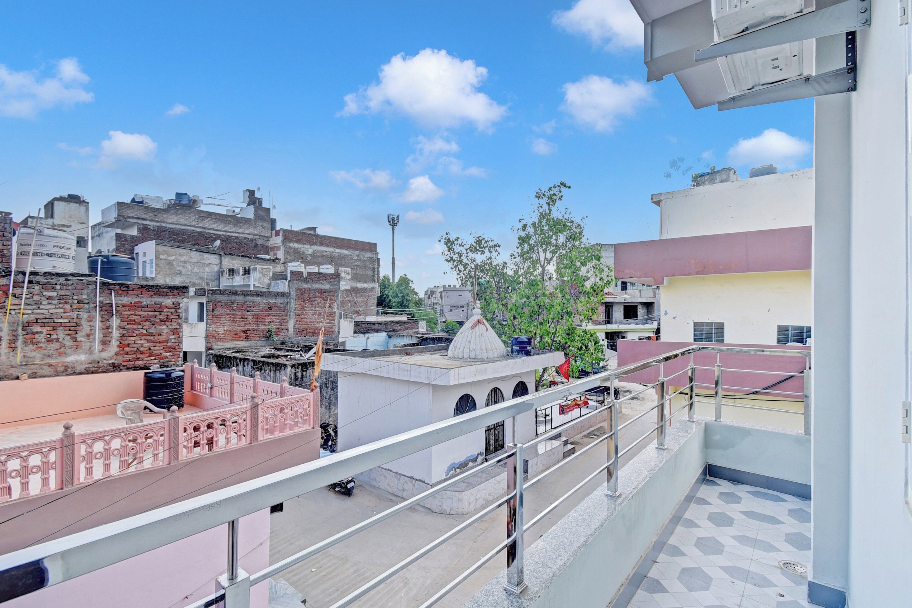 Una terraza en la azotea con barandilla de metal, vistas panorámicas de la ciudad y un cielo despejado.