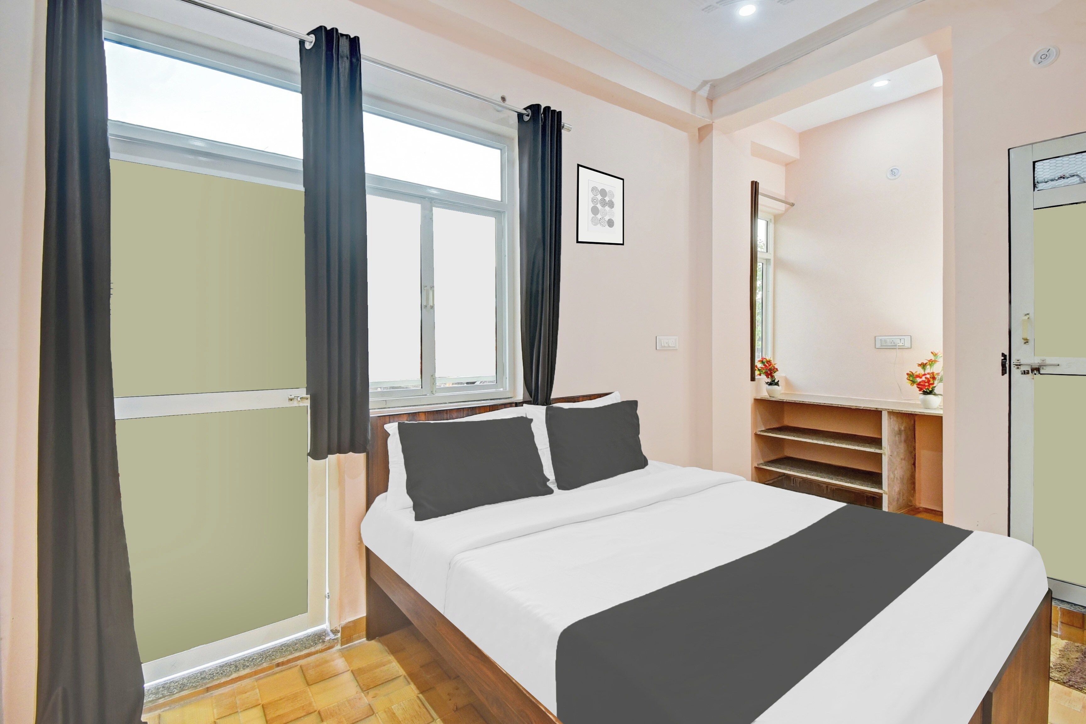 Un dormitorio con cama, ventana con cortinas, mesita de noche con un florero y un armario.