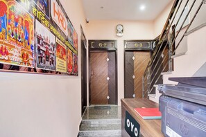 Un hall d’hôtel avec un escalier, deux portes portant les numéros G-2 et G-3, et un comptoir de réception sur lequel est affiché un panneau indiquant « OYO ».
